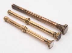 Three yellow metal propelling pencils:, one with scroll engraved hexagonal shaft,