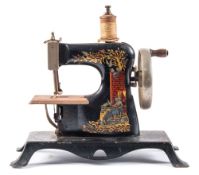 An early 20th century tinplate sewing machine:, with gilt transfer decoration , 22.5cm wide..