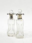 A pair of glass scent bottles of waisted form, with silver collars,