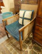 Edwardian mahogany bergere armchair on square tapering supports and castors