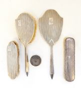 George V silver-backed part dressing table set comprising hand mirror, hairbrush and clothes brush,