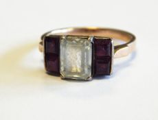 A gold coloured metal ring set four ruby coloured stones flanking possible white sapphire and a 9ct