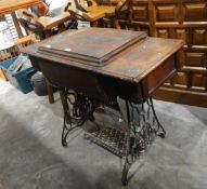 An old treadle sewing machine on original table with cast iron supports and treadle platform,