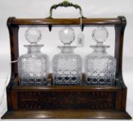 Early 20th century oak tantalus with three cut glass decanters,