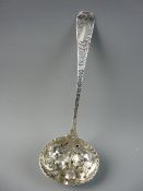 AN ORNATE SILVER SUGAR SIFTER, the bowl with raised fruit and leaf decoration and the handle with