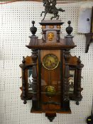 AN UNUSUAL VIENNA TYPE WALL CLOCK, pendulum driven brass faced movement in a walnut and mixed wood