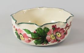 LLANELLY POTTERY BOWL painted with wild-roses and having a crimped rim, stencilled mark to base,