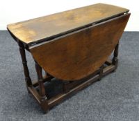 AN EARLY NINETEENTH CENTURY OAK DROP-LEAF GATE LEG TABLE having shaped apron above corner turned