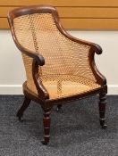 AN ANTIQUE MAHOGANY FRAMED CANE WORK CHAIR having carved terminals to the arms and on turned