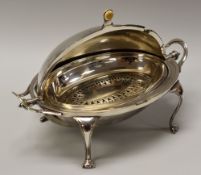 AN EPNS BREAKFAST WARMER with visor-form cover, raised on four bow supports and with loop side