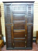 AN ANTIQUE OAK CORNER CUPBOARD with long centre door and short lower door on decorative brass hinges