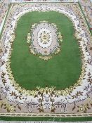 A GREEN GROUND INDIAN HAND KNOTTED WOOLLEN CARPET with cream and mushroom coloured border and