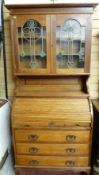 AN ARTS & CRAFTS STYLE OAK BUREAU BOOKCASE, the top with inverted crown over twin glazed doors