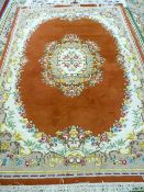 A 20th CENTURY INDIAN HAND KNOTTED CARPET with rust ground centre and border, brightly coloured