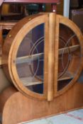 An Art Deco circular drum-type china cabinet with panelled and coloured glazed doors
