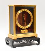 A JAEGER LECOULTRE ATMOS CLOCK with red marble effect face and side panels, brass chapter ring