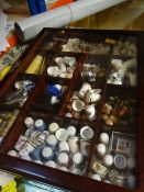 A modern table top compartmented cabinet containing a quantity of porcelain, thimbles and other