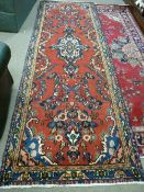 A FULL PILE RED GROUND PERSIAN RUNNER with floral medallion design, 300 x 100 cms