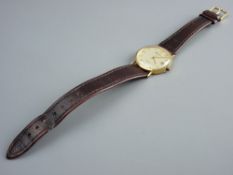 A GENT'S NINE CARAT GOLD ENCASED CIRCULAR DIAL GENEVE CALENDAR WRISTWATCH with leather strap, 16