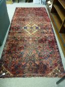 A RED GROUND PERSIAN RUNNER with all over design and central stepped medallion, 264 x 118 cms