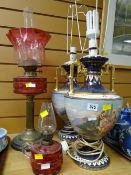 An antique oil lamp with cranberry glass reservoir and shade together with a pair of pottery table