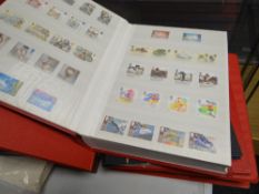 Four red stamp albums and a black stamp album all well stocked with mainly British content