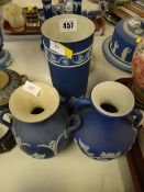 Three items of blue Wedgwood Jasperware comprising two twin-handled vases and a cylindrical vase