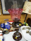 An Art Nouveau antique oil lamp on a pottery base with cranberry glass shade