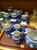A large quantity of blue Wedgwood Jasperware jugs with EPNS lids