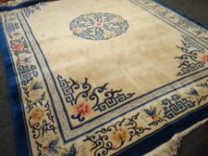 A large Oriental ivory and blue bordered rug, 365 x 274cms