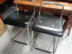 A pair of chrome and black leather bar / breakfast stools