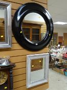 A modern wide black framed circular bevelled wall mirror together with a painted wood wall mirror