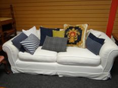 A large loose covered chesterfield-style sofa together with a selection of cushions.