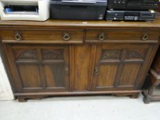A mid twentieth century oak sideboard, two drawers above a two cupboard base with carving to the