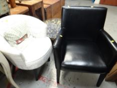 A modern upholstered club-style armchair together with a black leather armchair