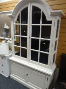 A modern white painted dome topped display cabinet above a two-cupboard base