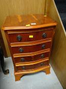 A small reproduction walnut bow fronted four-drawer chest / lamp table