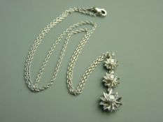 AN EIGHTEEN CARAT WHITE GOLD TRIPLE GRADUATED FLORAL PENDANT, diamond set with fine link chain