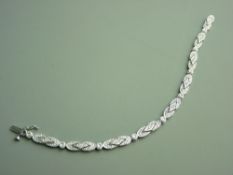 A NINE CARAT WHITE GOLD DIAMOND SET ARTICULATED LINK BRACELET having approximately seventy two