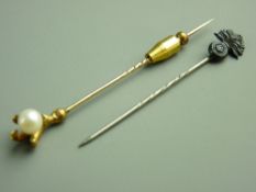 A YELLOW METAL STICKPIN with pearl in a claw and a military head stickpin