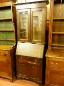 A VINTAGE OAK BUREAU BOOKCASE with twin glazed upper doors above a sloped fall front, single base