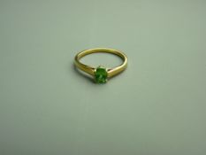 AN EIGHTEEN CARAT GOLD TSAVORITE DRESS RING having an oval faceted solitaire, 5 x 4 mm, moderate