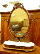 A VICTORIAN MAHOGANY SWING DRESSING MIRROR, oval framed with carved top detail and supports on an