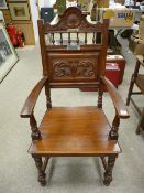 A 1914 OAK EISTEDDFOD CHAIR having a shell carved top rail, spindle gallery and lower leaf carved