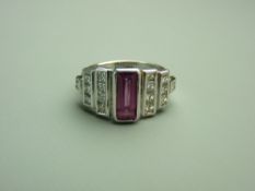 A FOURTEEN CARAT WHITE GOLD PINK SAPPHIRE & DIAMOND DRESS RING, the oblong emerald cut faceted