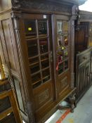 Continental carved oak two glass door cabinet on a raised stretcher base