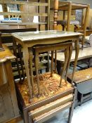 A nest of three tile topped tables together with a nest of three carved wood and glass topped