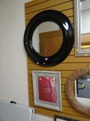A very large circular wide black framed bevelled mirror together with a smaller painted wooden