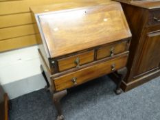 A vintage oak bureau with two short above one long drawers standing on ball & claw feet