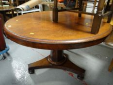 An antique circular Regency-style mahogany dining table on central column support and tripod bun